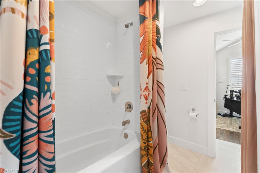 3060 Woodside Avenue Naples, FL 34112 - Photo 21 of 36 a bathroom with a bathtub and a shower curtain