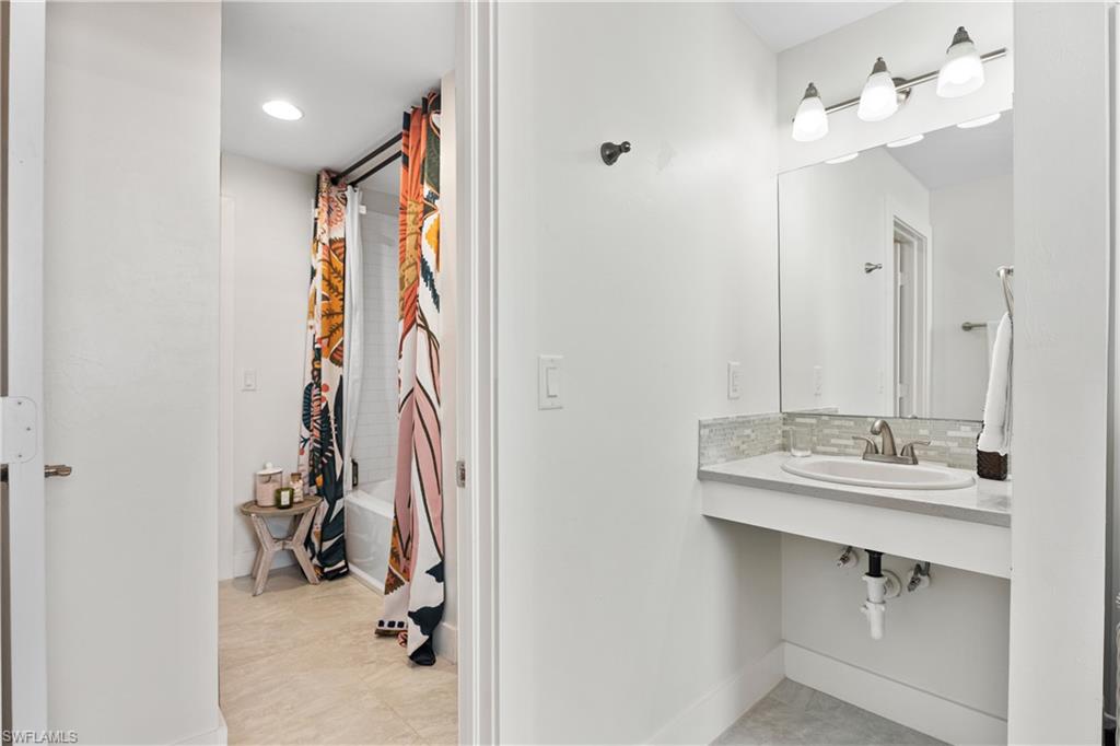 3060 Woodside Avenue Naples, FL 34112 - Photo 22 of 36 a bathroom with a sink a mirror and shower
