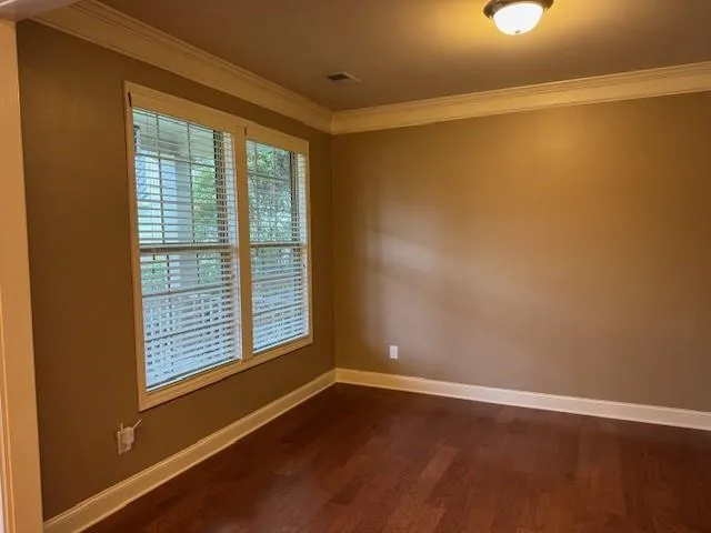 a view of an empty room with a window and hardwood floor
