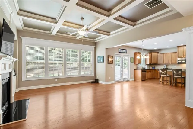 a view of an empty room with wooden floor and a kitchen