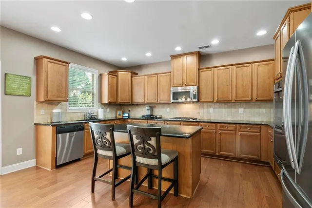 a kitchen with stainless steel appliances granite countertop wooden cabinets a stove top oven a sink and dishwasher