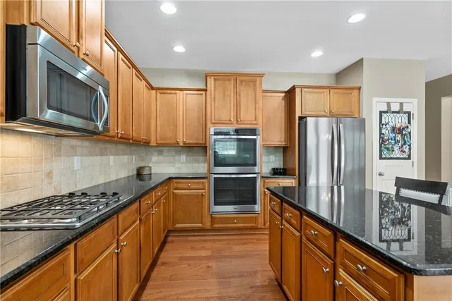 a kitchen with stainless steel appliances granite countertop a refrigerator and a stove top oven