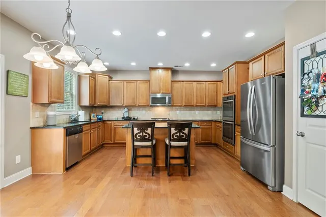 a kitchen with kitchen island granite countertop stainless steel appliances a center island a stove a dining table and chairs