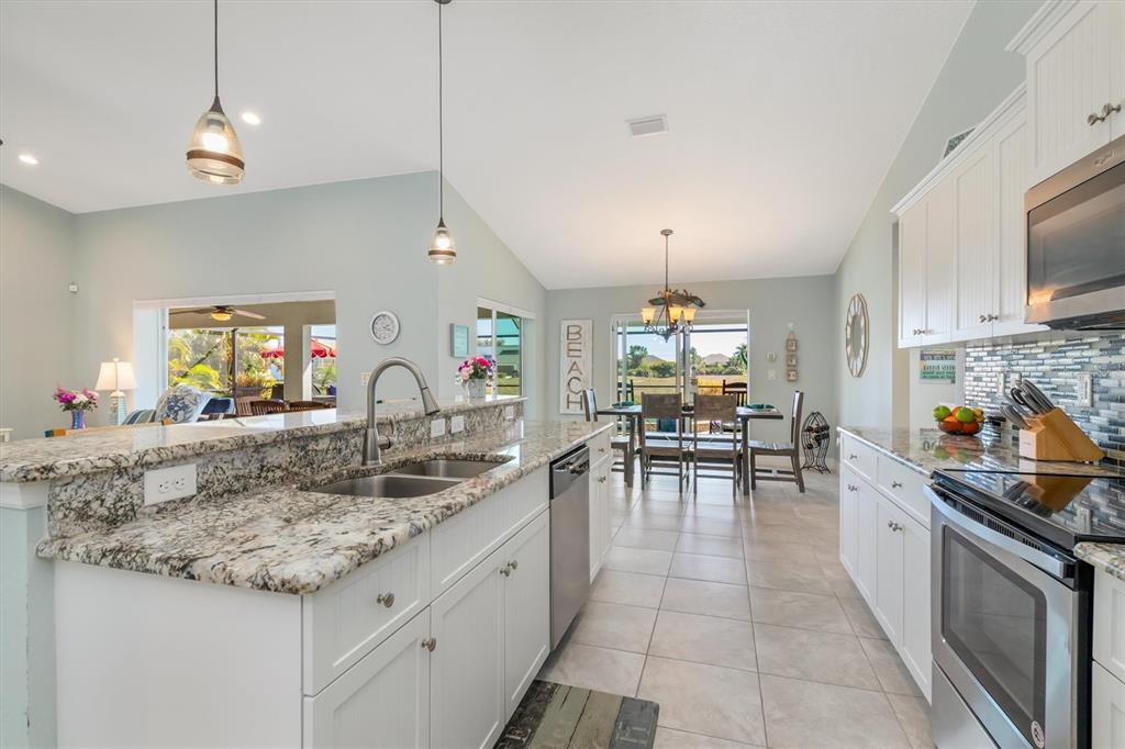 259 Marker Road Rotonda West, FL 33947 - Photo 11 of 37 a kitchen with granite countertop a stove a sink a dining table and chairs with wooden floor