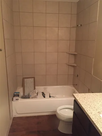 a bathroom with a granite countertop toilet a sink and bathtub