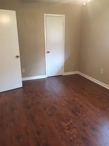 an empty room with wooden floor and white door