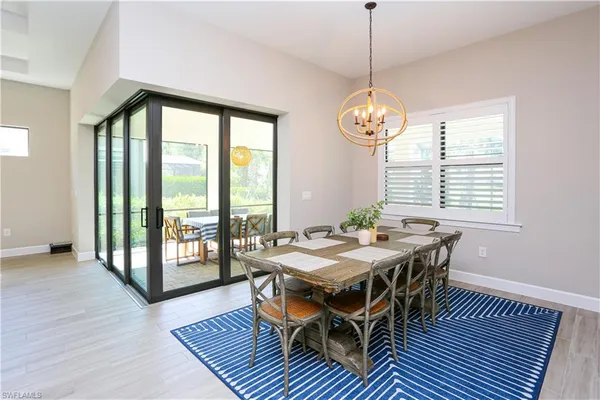 a dining room with wooden floor a chandelier a wooden table and chairs