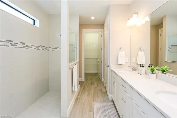 a spacious bathroom with a double vanity sink a mirror and a shower