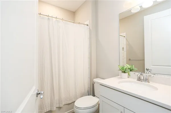 a bathroom with a sink a toilet a mirror and shower curtain