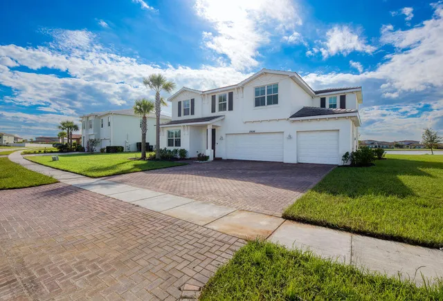 a view of a white house with a big yard and large trees