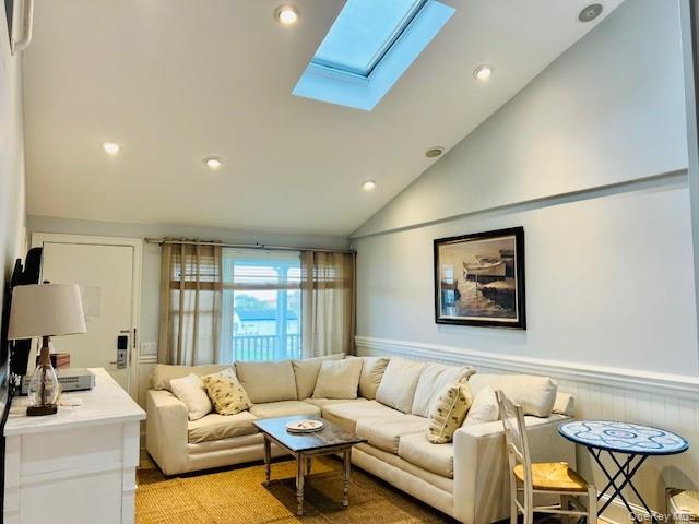 231 Dune Road, Unit 905 Westhampton Beach, NY 11978 - Photo 2 of 24 Living room featuring vaulted ceiling, recessed lighting, a skylight, and a wainscoted wall