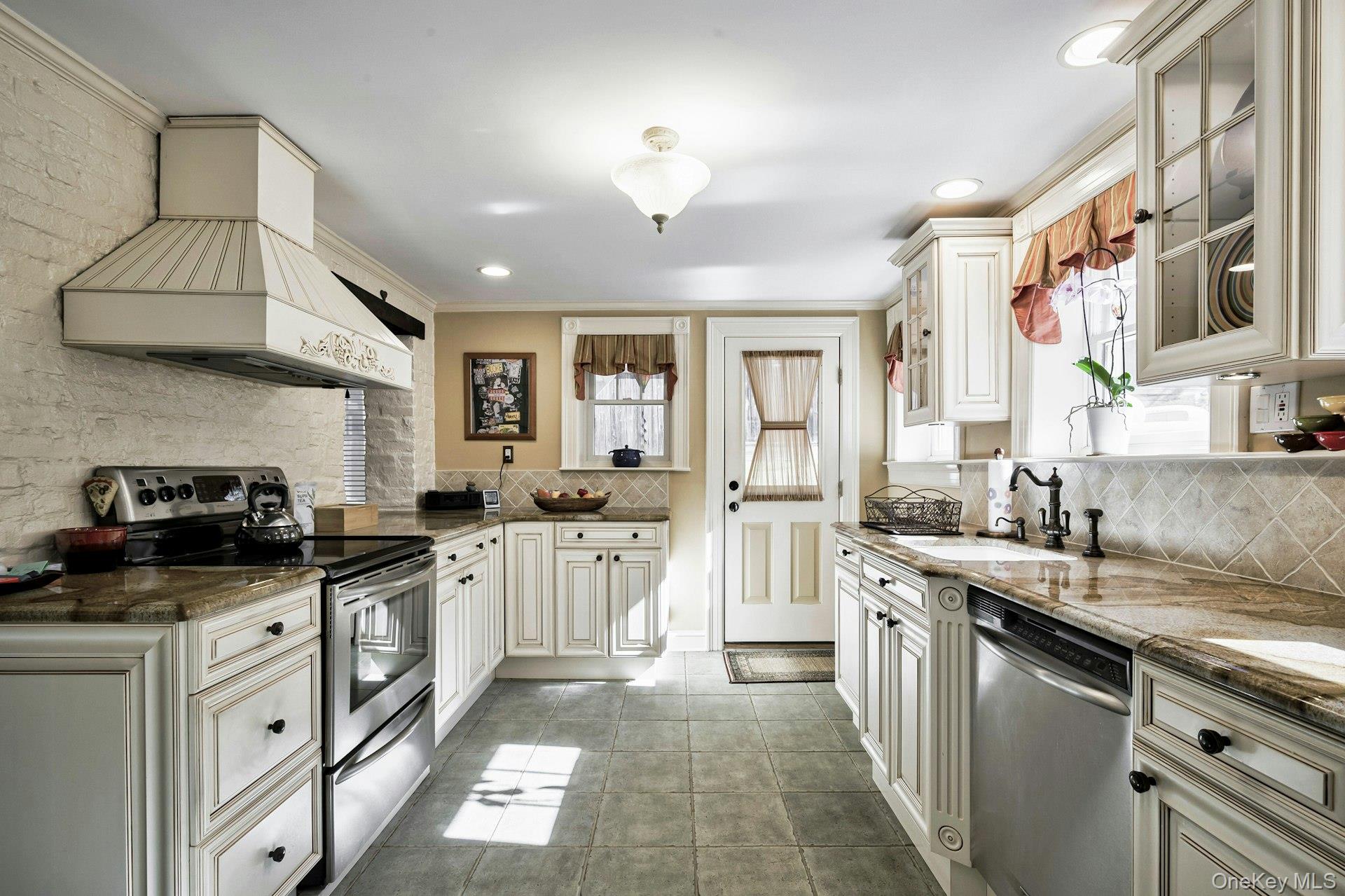 126 Cove Road Oyster Bay, NY 11771 - Photo 12 of 42 Kitchen with stainless steel appliances, premium range hood, dark stone countertops, decorative backsplash, and crown molding