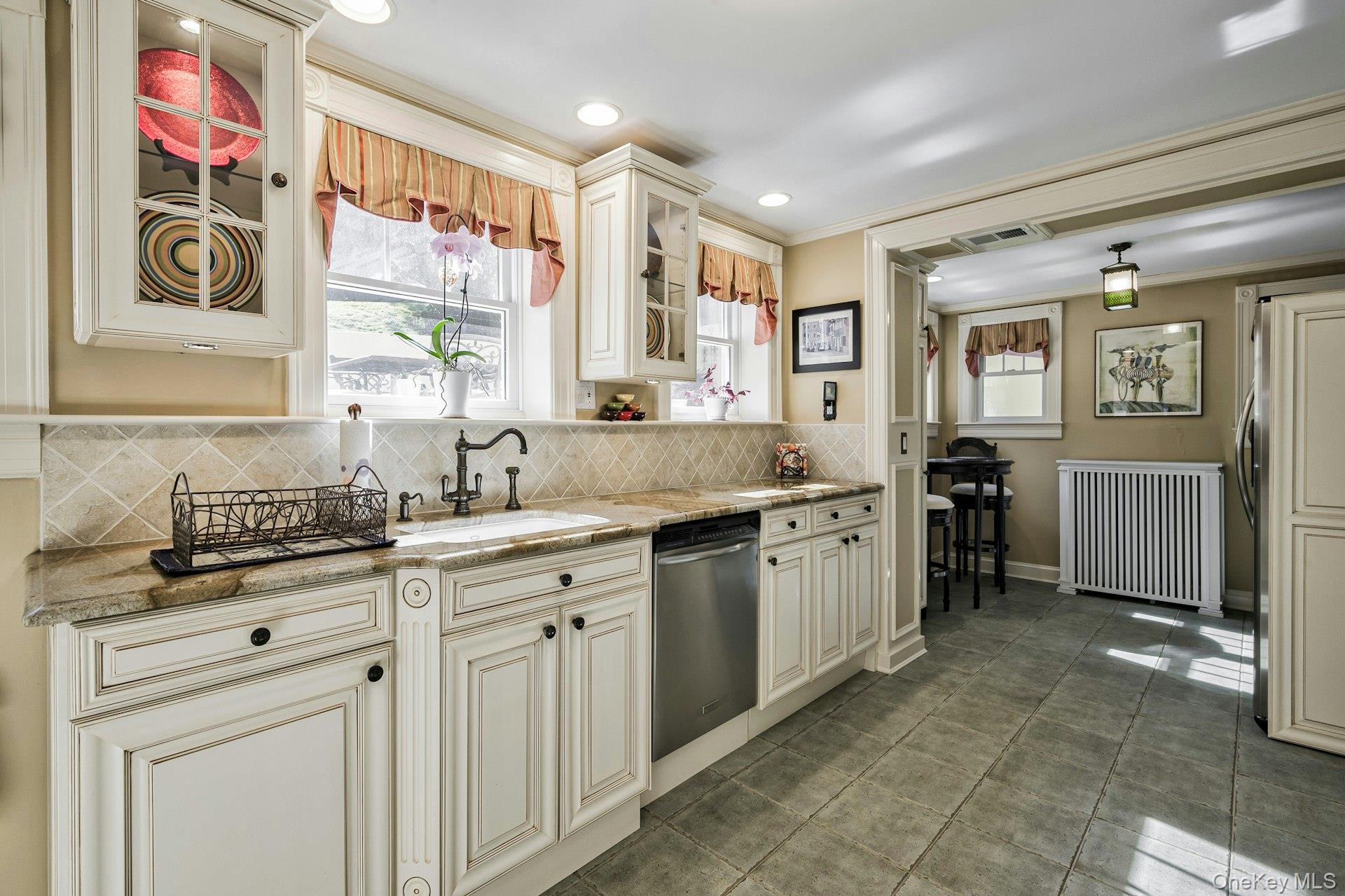 126 Cove Road Oyster Bay, NY 11771 - Photo 14 of 42 Kitchen with tasteful backsplash, light stone countertops, radiator, cream cabinetry, and crown molding