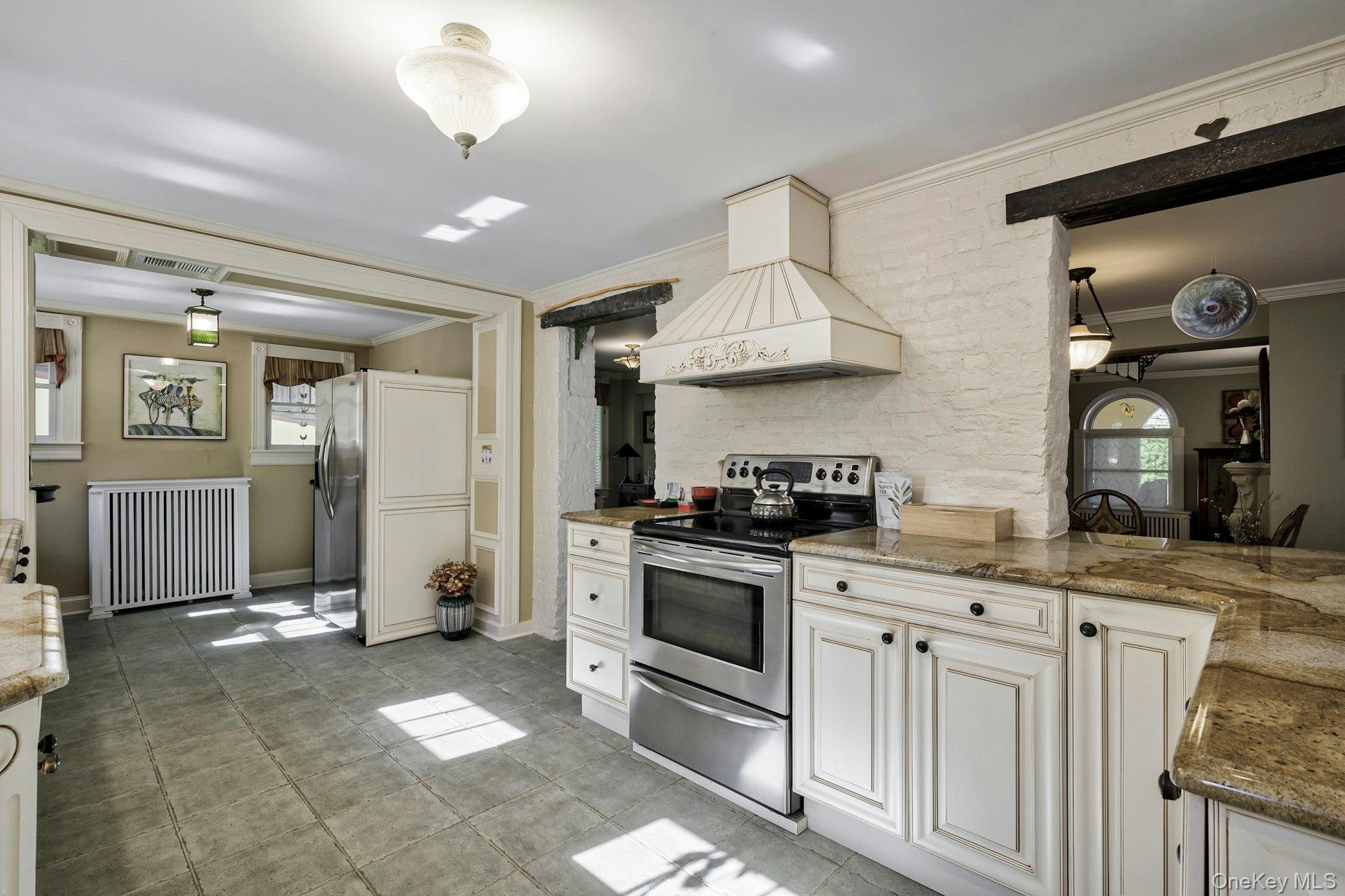 126 Cove Road Oyster Bay, NY 11771 - Photo 15 of 42 Kitchen with light stone countertops, stainless steel appliances, custom exhaust hood, hanging light fixtures, and crown molding