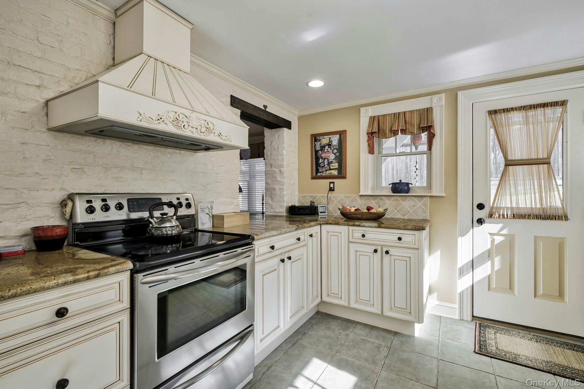126 Cove Road Oyster Bay, NY 11771 - Photo 18 of 42 Kitchen featuring stainless steel electric range oven, dark stone countertops, tasteful backsplash, light tile patterned floors, and ornamental molding