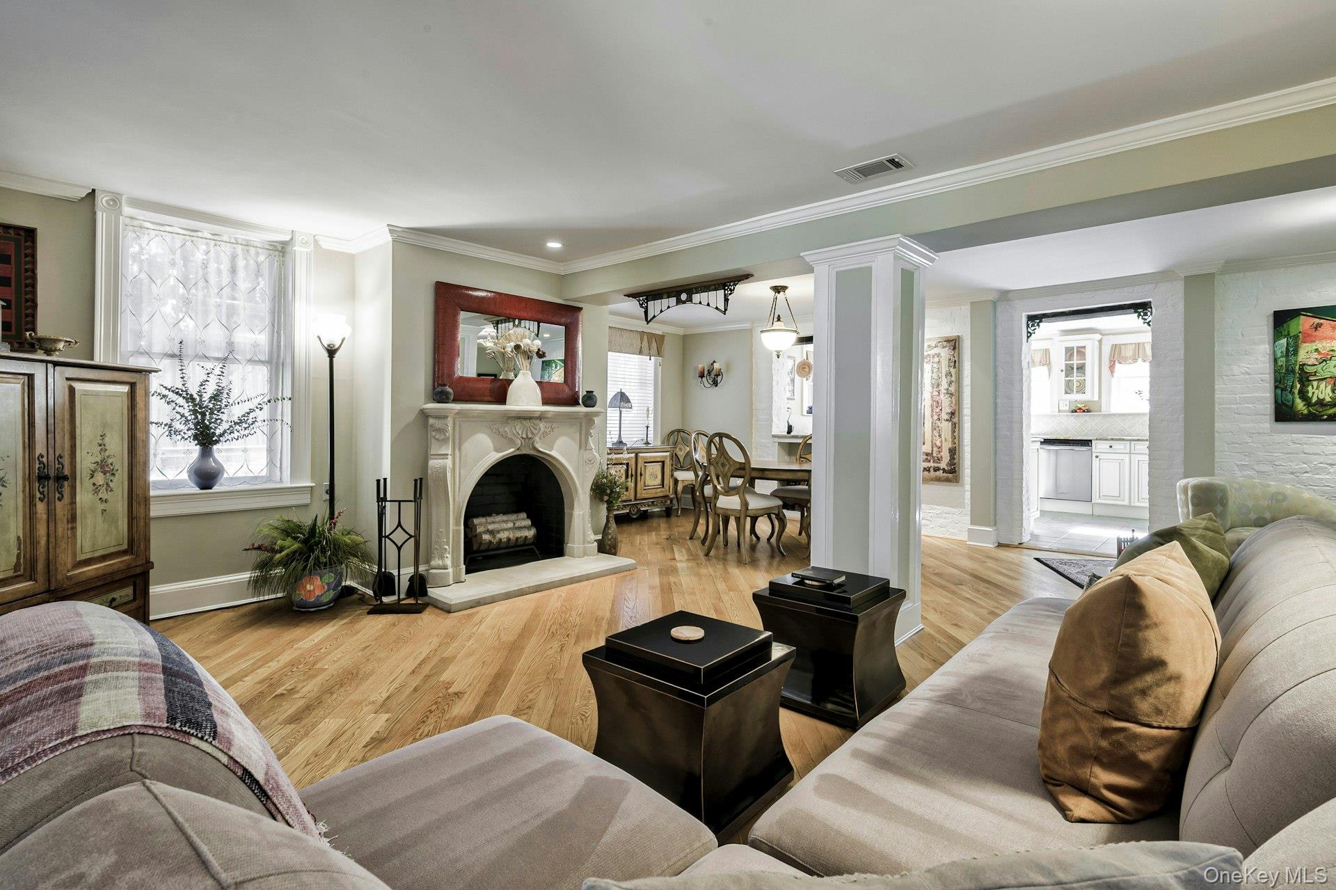 126 Cove Road Oyster Bay, NY 11771 - Photo 19 of 42 Living room featuring light wood finished floors, a fireplace with raised hearth, crown molding, and decorative columns