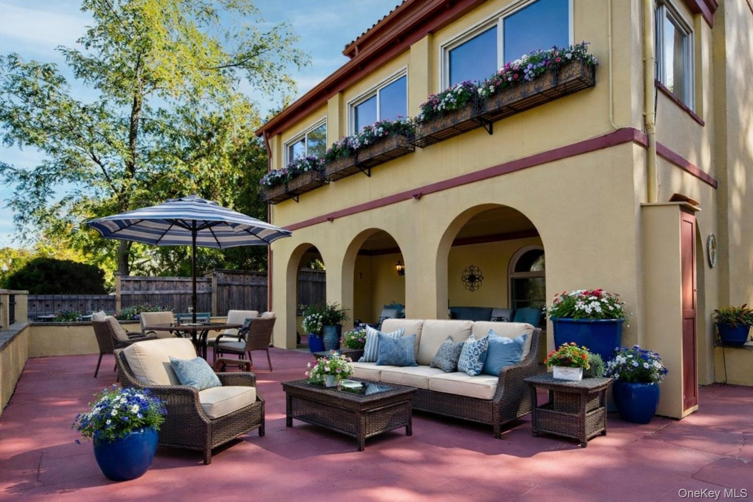 126 Cove Road Oyster Bay, NY 11771 - Photo 2 of 46 a view of a patio with couches table and chairs under an umbrella with a fire pit