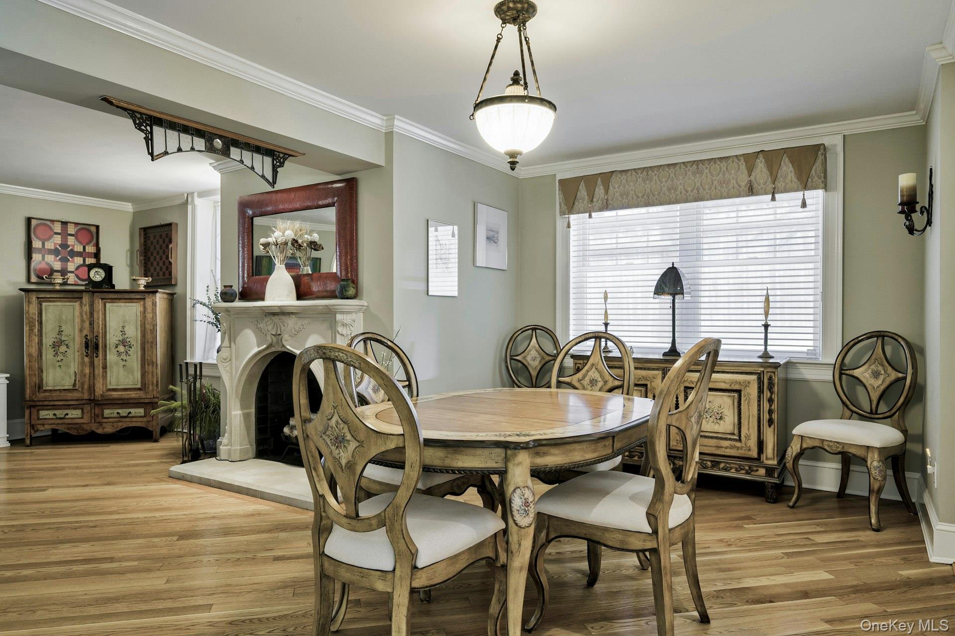 126 Cove Road Oyster Bay, NY 11771 - Photo 22 of 42 Dining area with ornamental molding, a fireplace with raised hearth, and wood finished floors