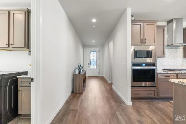 a view of a hallway with wooden floor and a kitchen