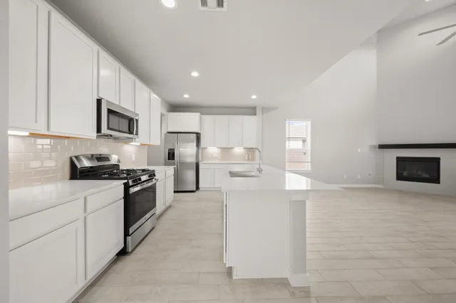 a kitchen with stainless steel appliances granite countertop a stove top oven a sink and white cabinets