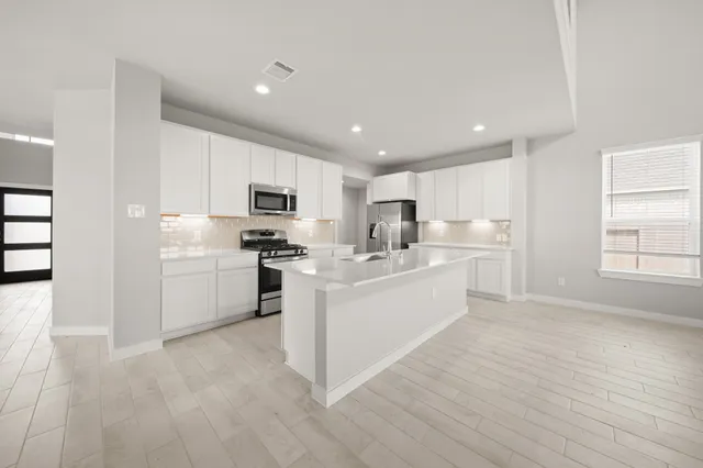 a kitchen with white cabinets and stainless steel appliances