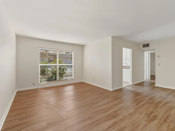 a view of an empty room with wooden floor and windows