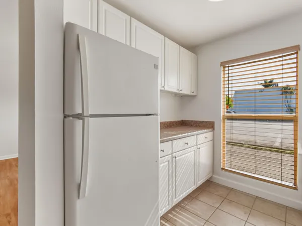 a kitchen with a refrigerator and white cabinets