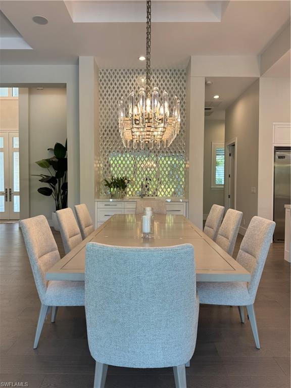 569 Neapolitan Way Naples, FL 34103 - Photo 9 of 50 Dining space featuring an inviting chandelier, recessed lighting, dark wood-style floors, and a raised ceiling