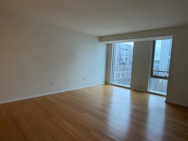 a view of an empty room with wooden floor and a window