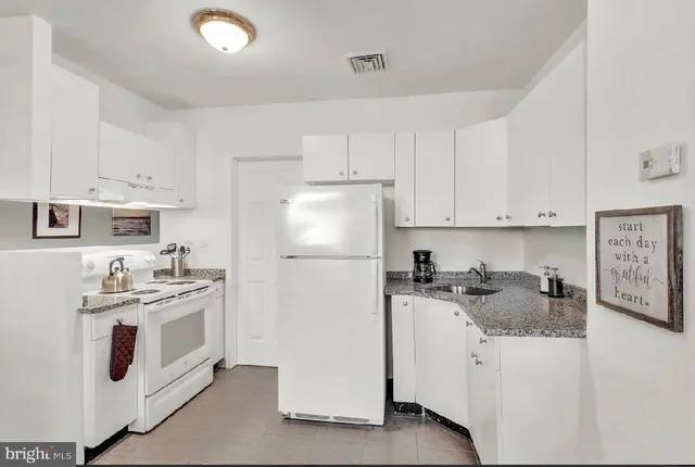 a kitchen with stainless steel appliances granite countertop a stove a refrigerator a sink a stove and white cabinets