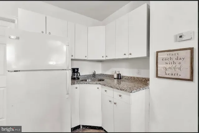 a kitchen with granite countertop white cabinets and white appliances