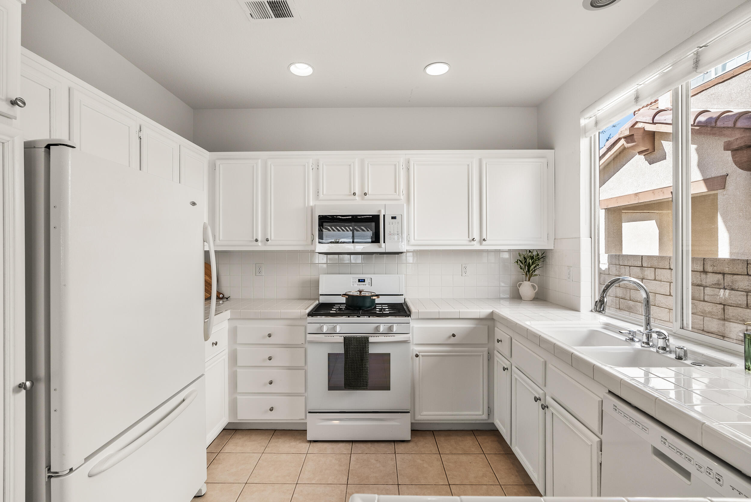 25803 Hammet Circle Stevenson Ranch, CA 91381 - Photo 13 of 32 a kitchen with white cabinets stainless steel appliances and a window