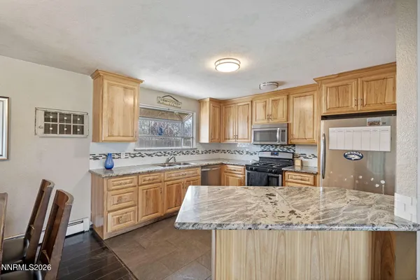 a kitchen with kitchen island granite countertop a stove top oven a sink a dining table and chairs
