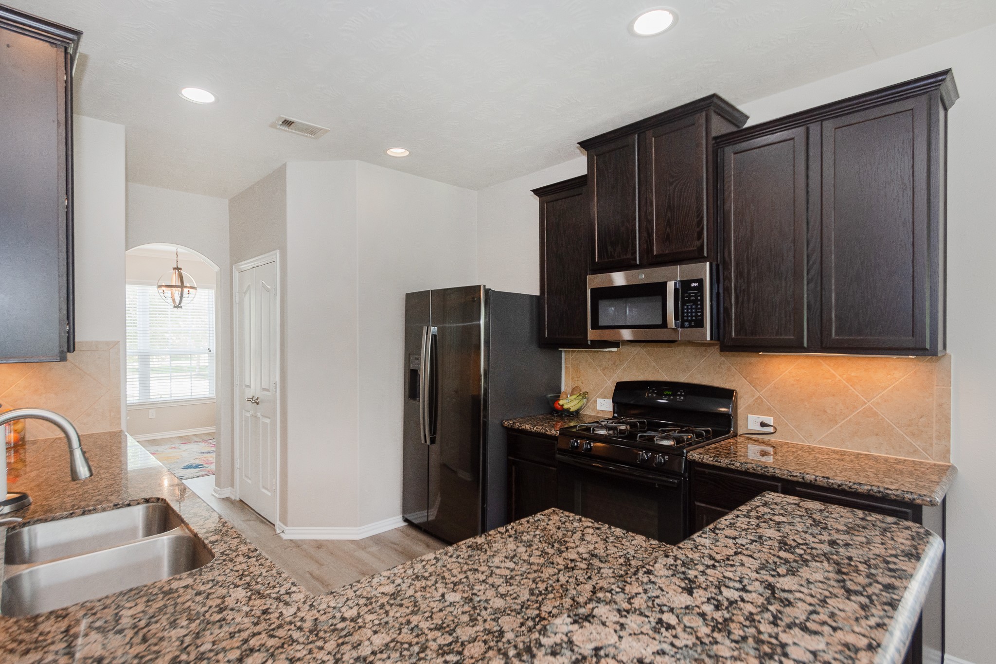 4907 Applewood Crest Lane Rosharon, TX 77583 - Photo 9 of 36 a kitchen with granite countertop wooden cabinets a refrigerator and a sink