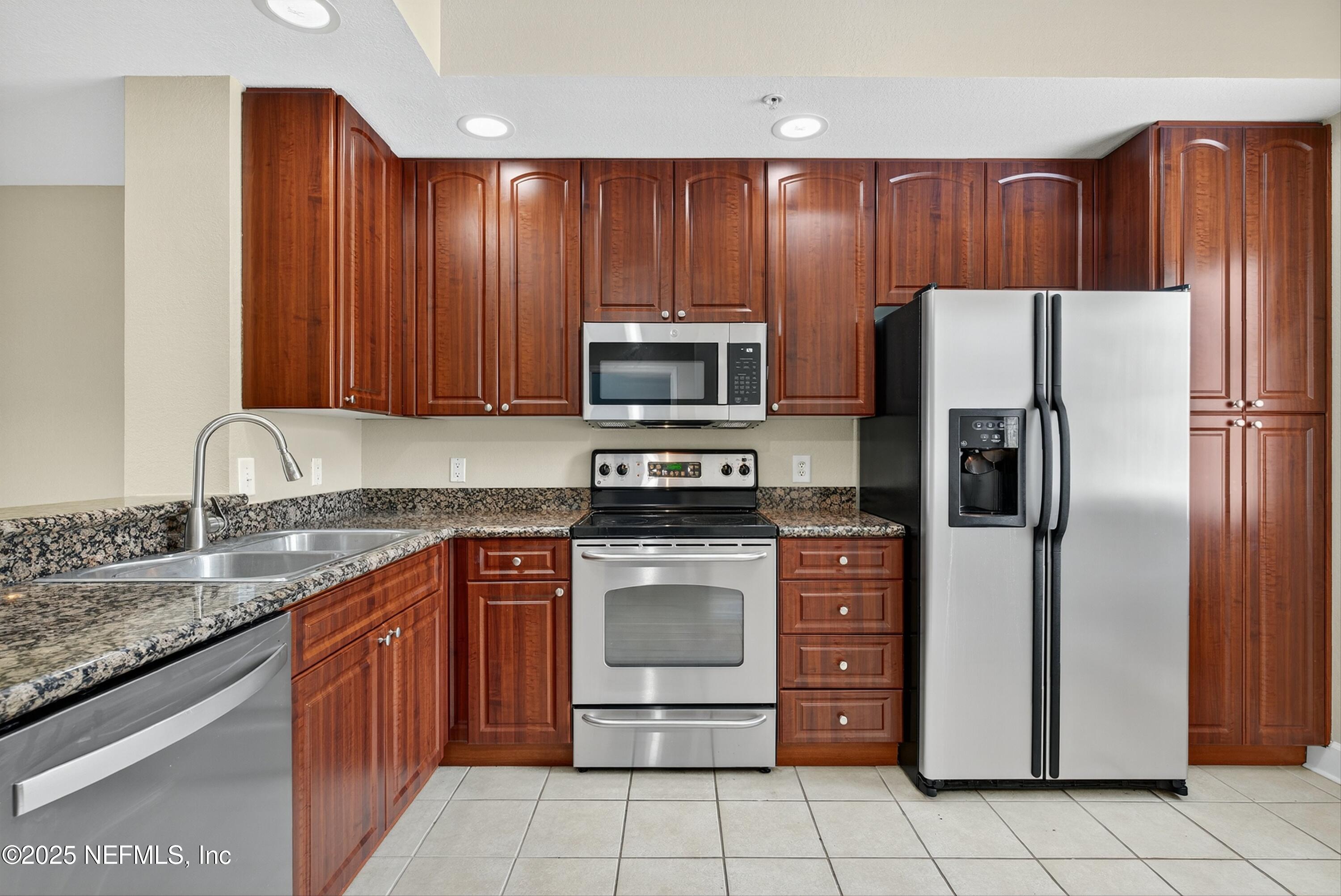 9745 Touchton Road, Unit 1625 Jacksonville, FL 32246 - Photo 32 of 69 a kitchen with granite countertop stainless steel appliances and wooden cabinets