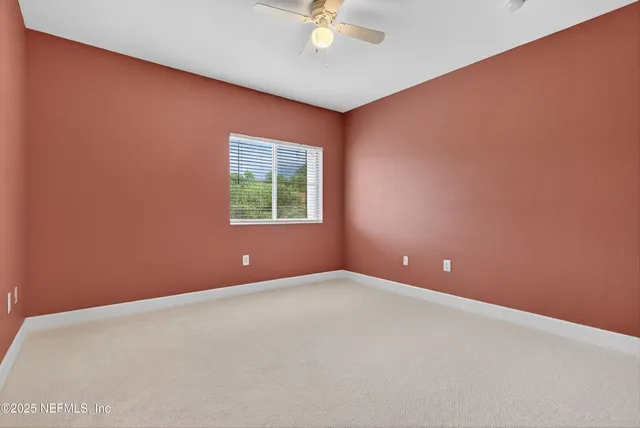 an empty room with chandelier fan and windows