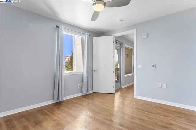 a view of an empty room with window and wooden floor