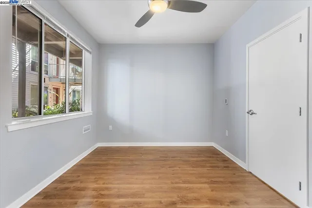a view of empty room with wooden floor and fan