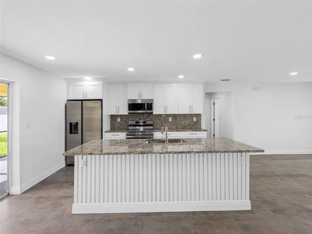 a kitchen with granite countertop white cabinets and a sink