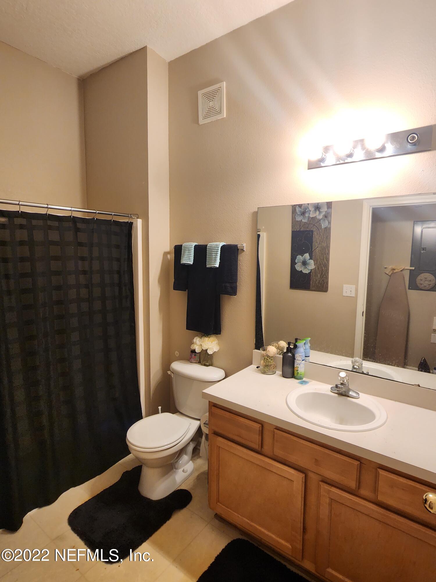 7920 Merrill Road, Unit 1704 Jacksonville, FL 32277 - Photo 8 of 11 a bathroom with a sink a toilet a mirror and shower curtain