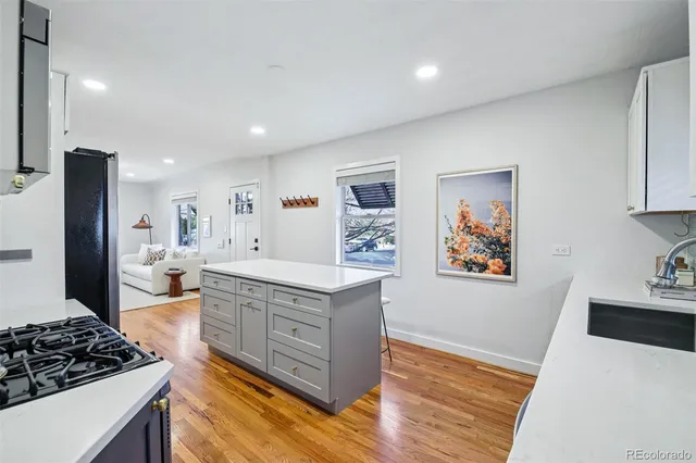 a large white kitchen with stainless steel appliances granite countertop a stove and a wooden floors