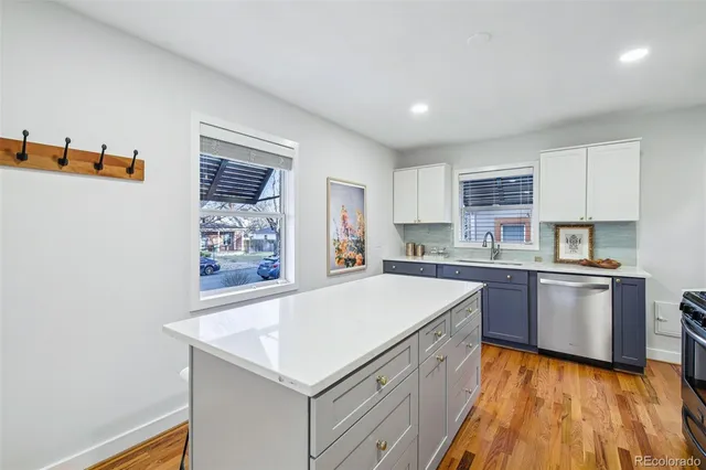 a large white kitchen with kitchen island a sink dishwasher stove with wooden floor