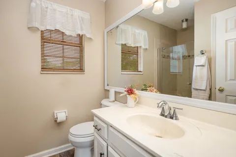 a bathroom with a granite countertop toilet a sink a mirror and a window