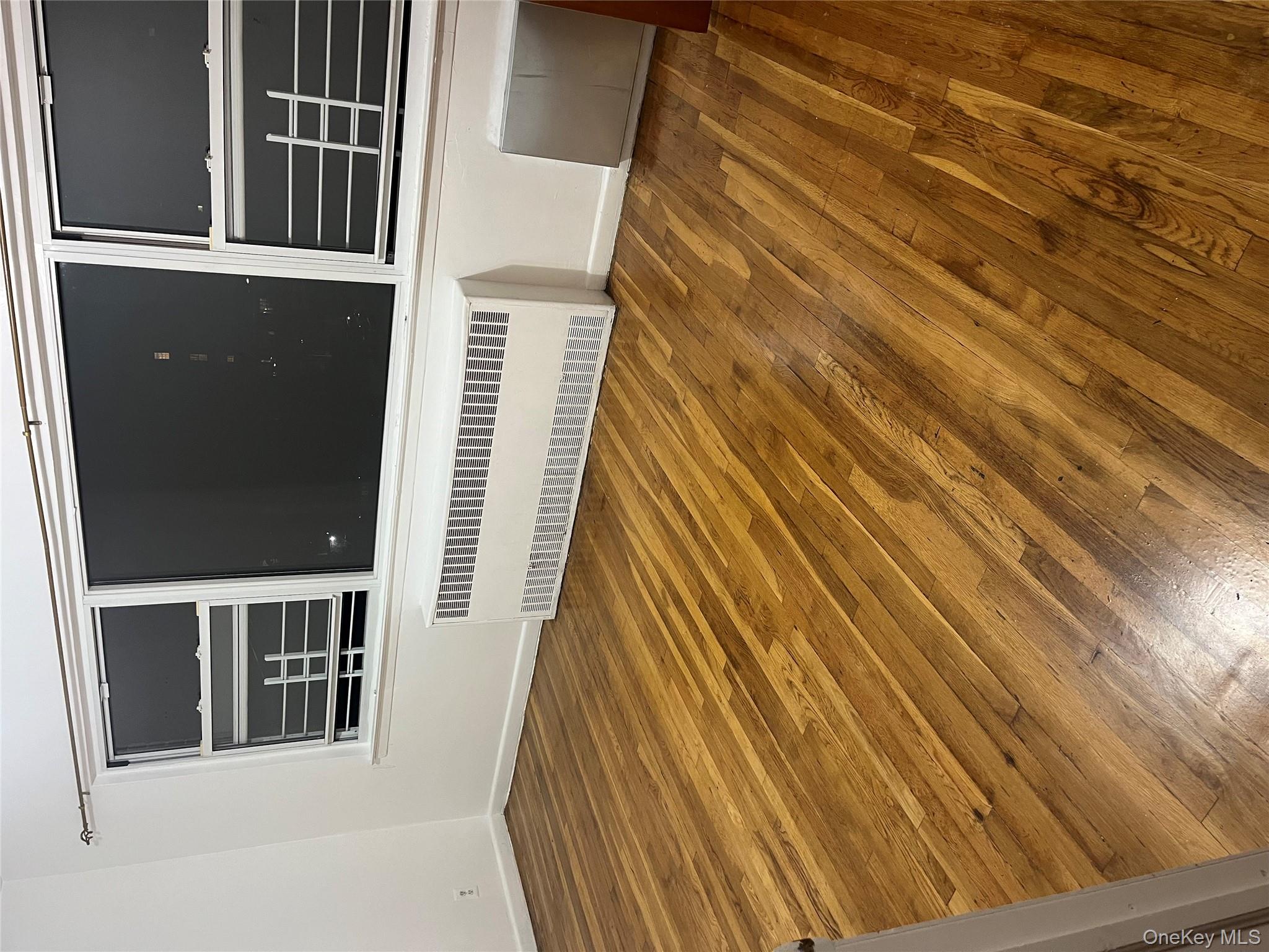 Unfurnished room featuring hardwood / wood-style flooring and radiator
