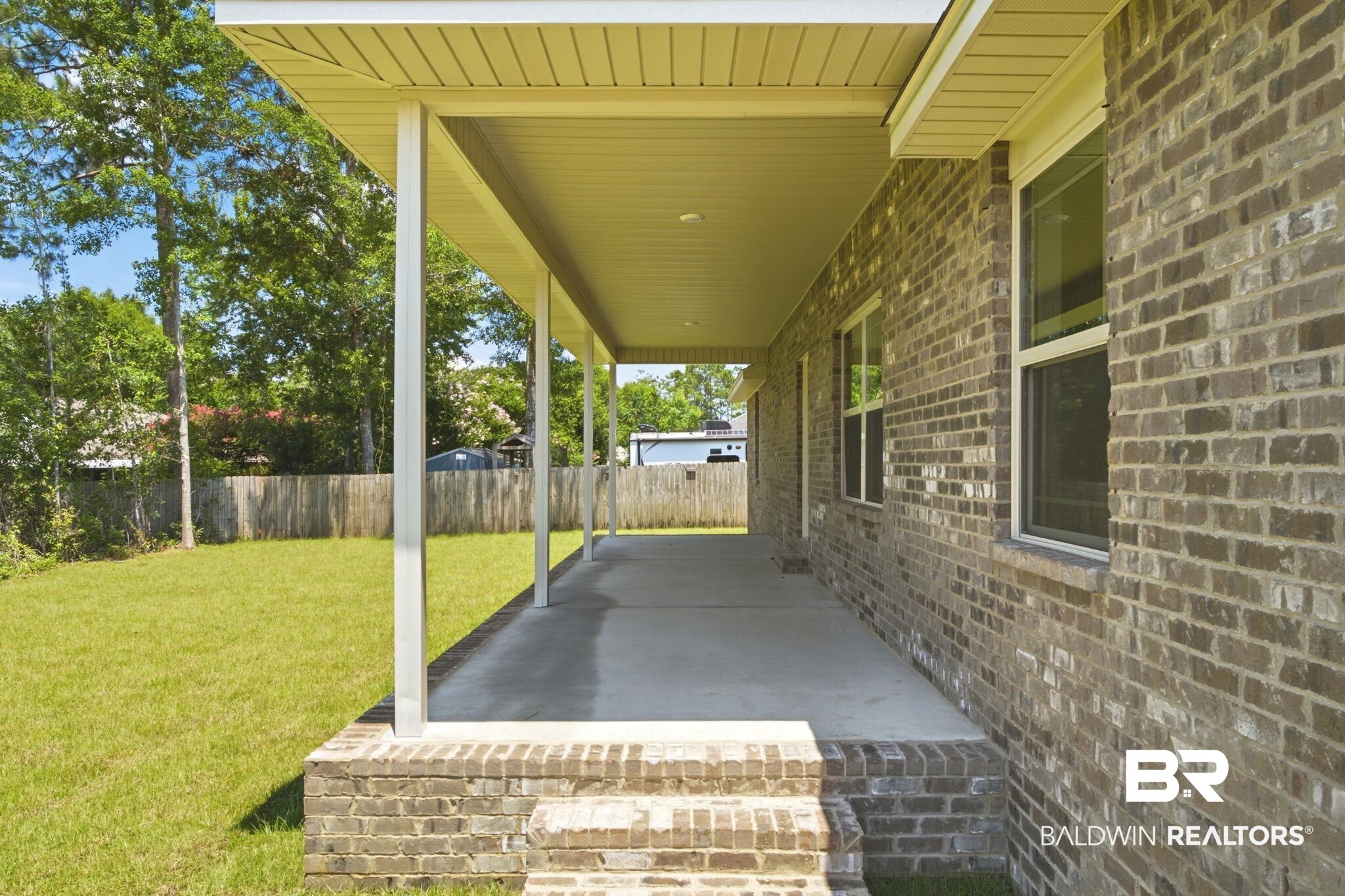 32656 Arbor Ridge Circle Lillian, AL 36549 - Photo 37 of 56 Expansive covered patio featuring a concrete surface, brick foundation, and multiple support columns