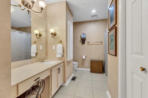 a spacious bathroom with a double vanity sink a toilet a mirror and shower
