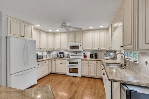 a kitchen with white cabinets stainless steel appliances and a window