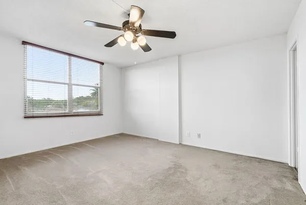 an empty room with windows and fan