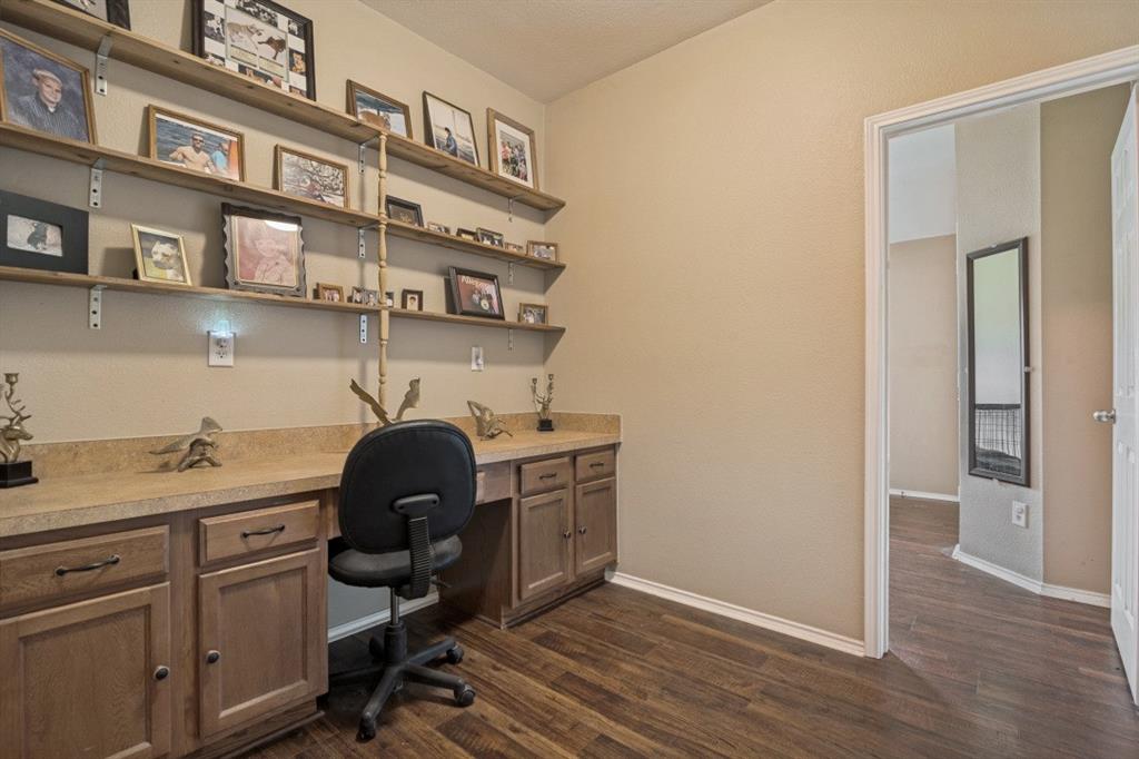 119 Robin Lane Forney, TX 75126 - Photo 21 of 27 Dedicated workspace featuring a built-in desk with a durable countertop, wood-finish base cabinets with dark hardware, and extensive open shelving