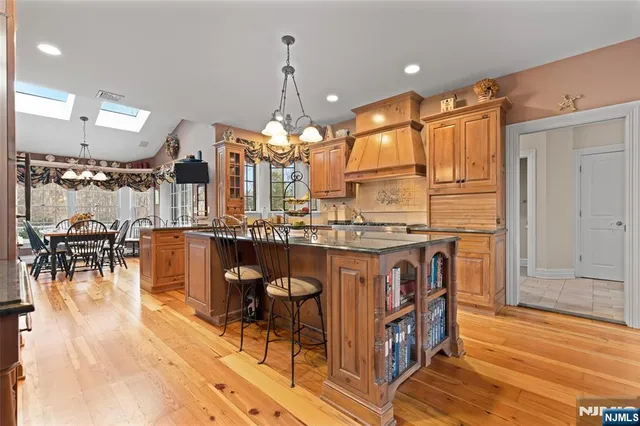 a open kitchen with stainless steel appliances granite countertop a stove top oven a dining table and chairs with wooden floor